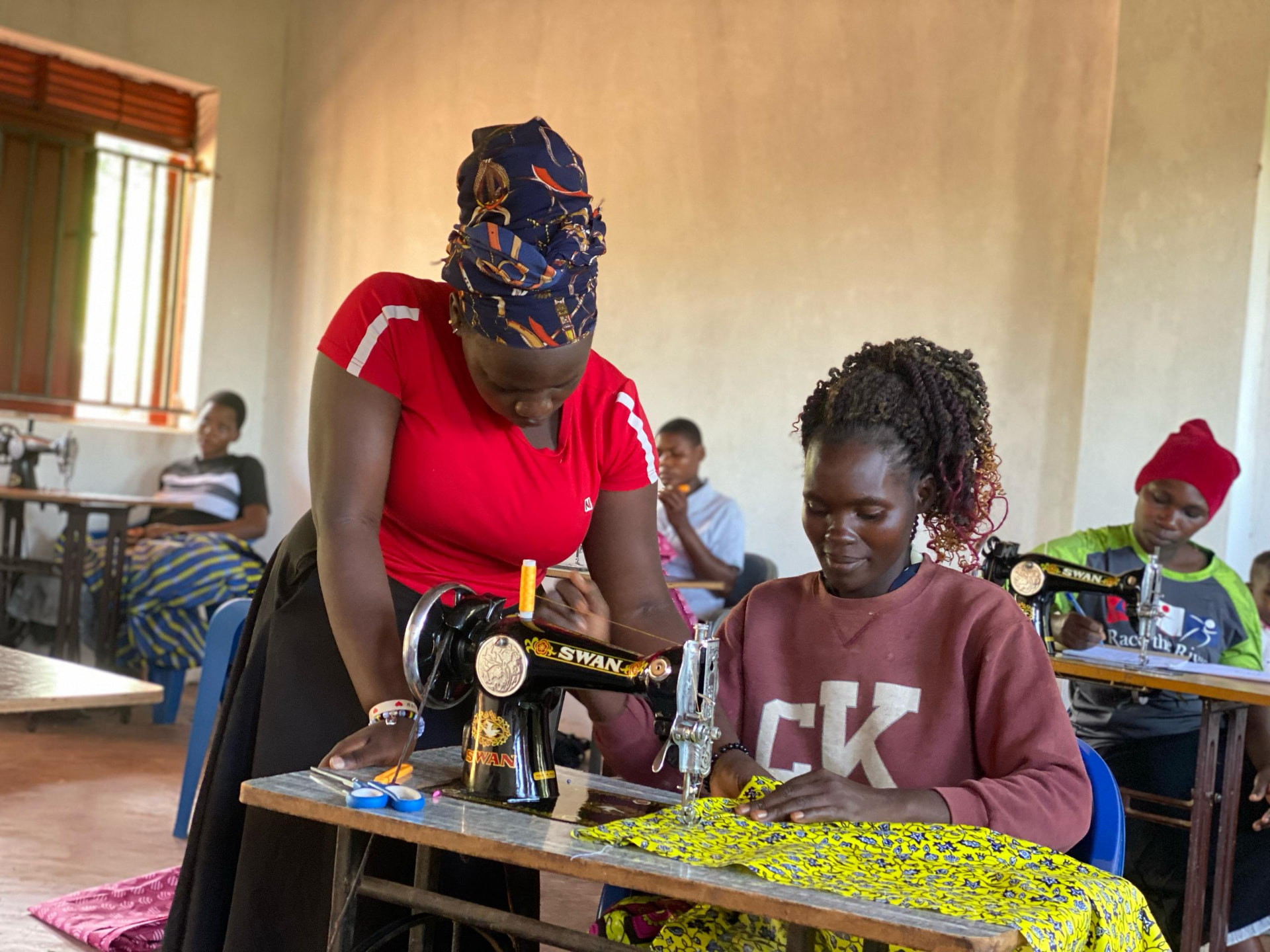 Trainer guiding a mother at a sewing machine