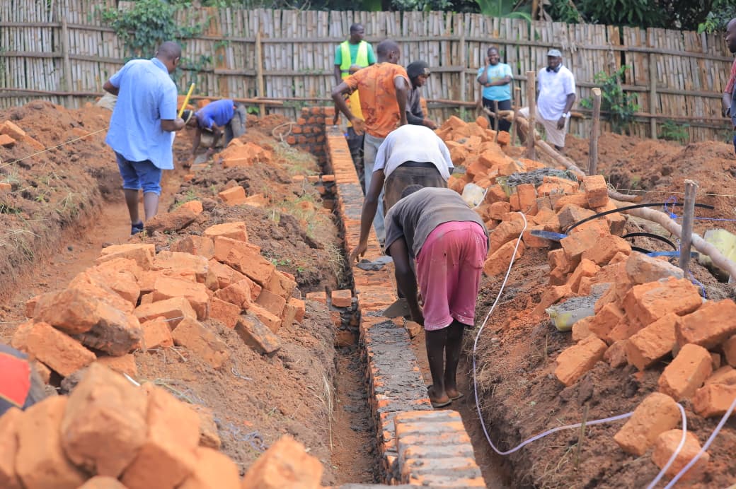 Workers laying the school foundations in a trench